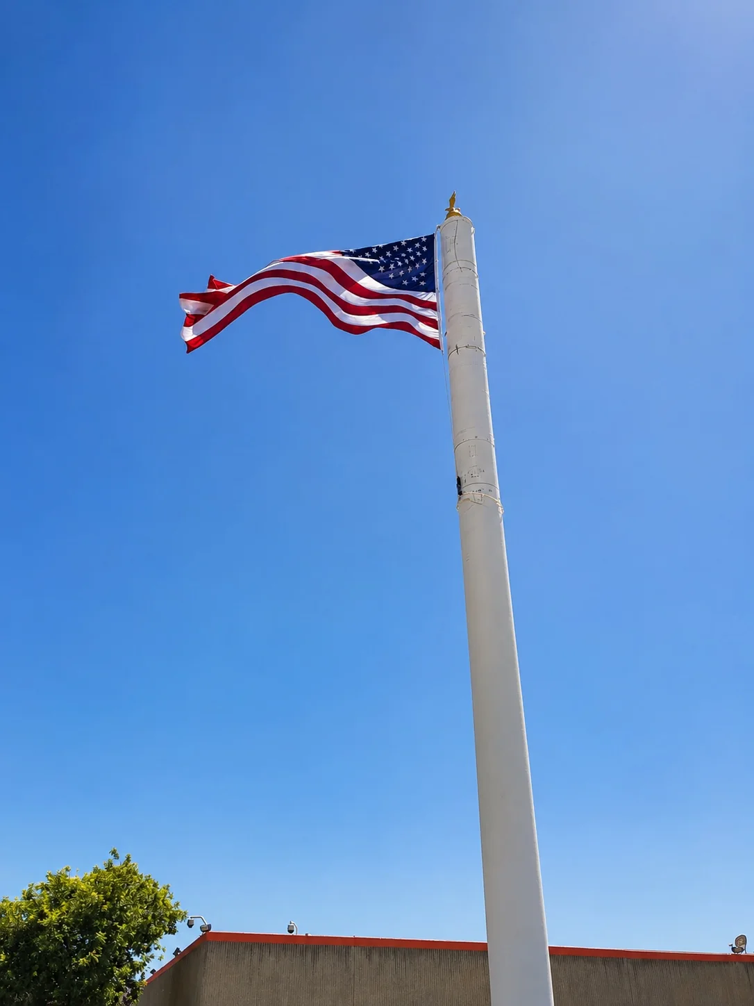 American flag flying on a tall flagpole beneath a clear blue sky